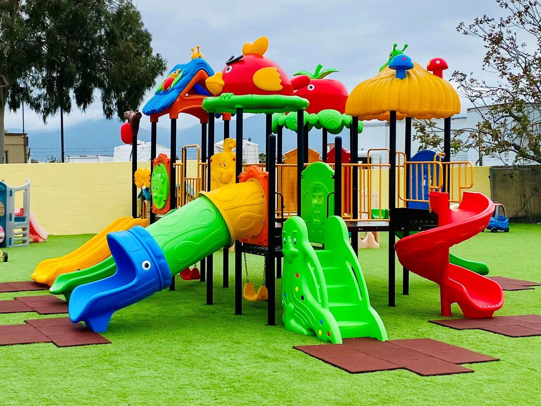 A colorful play structure with slides on the school’s turf playground.